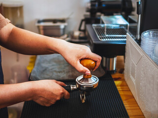 Close-up of hand Barista cafe making coffee with manual presses ground coffee using tamper at the...