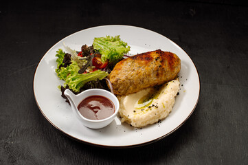 A dish of mashed potatoes with a steam cutlet and salad and ketchup on a wooden background