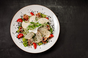 Diet salad with pear, bacon, lettuce and vegetables on a dark background