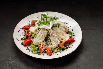 Diet salad with pear, bacon, lettuce and vegetables on a dark background