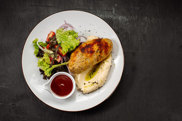 A dish of mashed potatoes with a steam cutlet and salad and ketchup on a wooden background