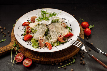 Diet salad with pear, bacon, lettuce and vegetables on a dark background
