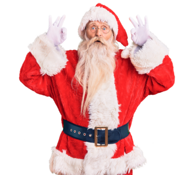Old senior man with grey hair and long beard wearing traditional santa claus costume looking surprised and shocked doing ok approval symbol with fingers. crazy expression