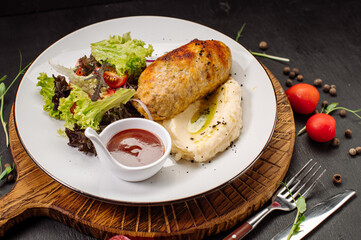 A dish of mashed potatoes with a steam cutlet and salad and ketchup on a wooden background