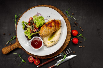 A dish of mashed potatoes with a steam cutlet and salad and ketchup on a wooden background