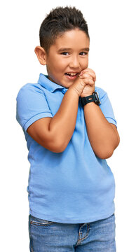 Little boy hispanic kid wearing casual clothes laughing nervous and excited with hands on chin looking to the side