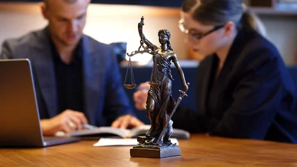 Fotobehang A lawyer meets with a new client. A young male lawyer in a suit sits at an office desk, shares legal advice, explains the inheritance process, tries to help. Legal advice concept © Vladislav