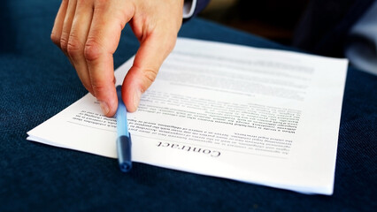 Close-up of a businessman putting his signature on a business agreement document. A man signs an...
