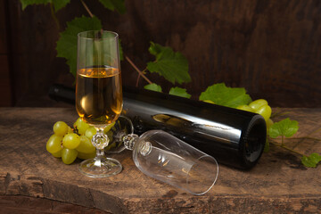 Still life with glass of white wine and grapes on vintage wooden background..