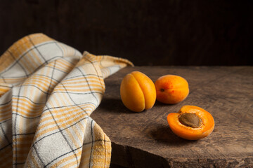 Apricot fruit whole and half on wooden background..