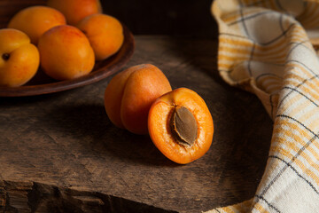 Apricot fruit whole and half on wooden background..