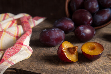 Fototapeta na wymiar Whole and half of purple plums on wooden background. .