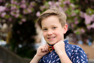 Fashion kid boy in shirt and bow tie. Funny kids emotions. Outdoor close up portrait of a cute little child playing outdoor. Portrait of pretty little kids face outside.