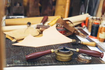 Tools and leather at cobbler workplace. Set of leather craft tools on background.