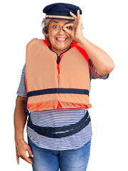 Senior woman with gray hair wearing nautical lifejacket smiling happy doing ok sign with hand on eye looking through fingers