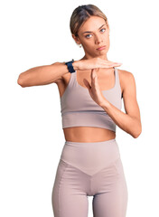 Beautiful caucasian woman wearing sportswear doing time out gesture with hands, frustrated and serious face