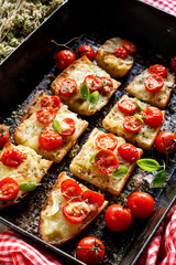  Grilled toast made with baguettes, mozzarella cheese and cherry tomatoes seasoned fresh basil in a baking tin, close up view