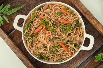 Tasty Vegetable hakka noodles in white plate and isolated background. Indo-Chinese vegetarian cuisine dish. Indian veg noodles with vegetables. Classic Asian meal - obrazy, fototapety, plakaty