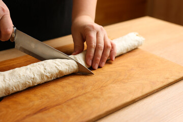 Fototapeta na wymiar Wrapped in a roll pita bread is cut. Preparation of a roll with cheese, fish and vegetables