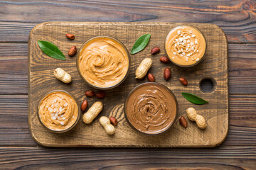 Glass jar with peanut butterin plate on table background, top view space for text and close up