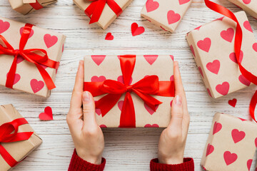 Give a gift on Valentine Day.Valentine gift. Beauty Woman hands holding Gift box with red bow over...