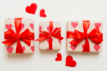 Top view photo of valentine day decorations gift box with red ribbon bow on colored background....