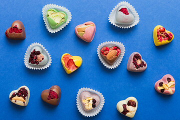 chocolate sweets in the form of a heart with fruits and nuts on a colored background. top view with space for text, holiday concept