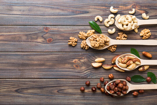 mixed nuts in white wooden spoon. Mix of various nuts on colored background. pistachios, cashews, walnuts, hazelnuts, peanuts and brazil nuts