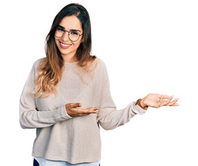 Beautiful hispanic woman wearing casual sweater and glasses inviting to enter smiling natural with...