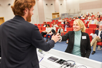 Speaker giving microphone to audience in business event