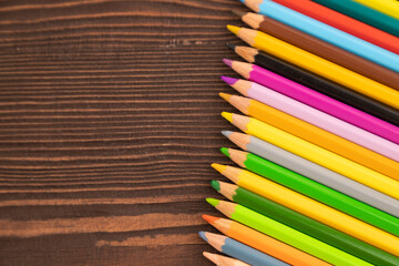 Obraz premium Set of watercolor pencils on brown wooden. Top view, copy space