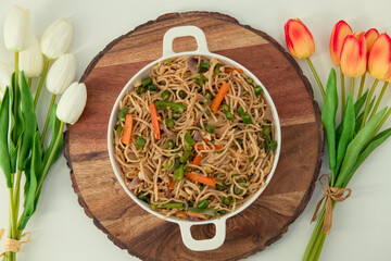 Tasty Vegetable hakka noodles in white plate and isolated background. Indo-Chinese vegetarian cuisine dish. Indian veg noodles with vegetables. Classic Asian meal..