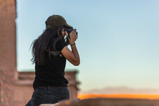 View of a western European woman taking photos at sunset in Ait Benhaddou, a small berber village on the High Atlas mountains, Central Morocco.