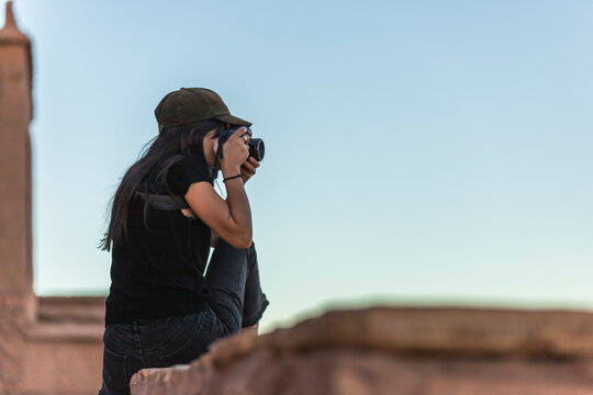 View of a western European woman taking photos at sunset in Ait Benhaddou, a small berber village on the High Atlas mountains, Central Morocco.