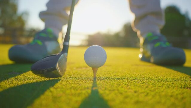 Slow motion golf sport concept, golfer hitting golf ball to hole for winner in golf course is beautiful fairway on sunset. Close up shot tee off on green grass for player playing in summer for relax