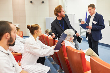 Doctor discussing with speaker over document at medical conference