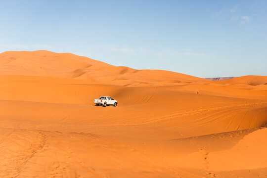 View of an off road vehicle driving across the Sahara desert sand dunes in Merzouga desert, Morocco.