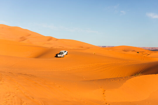 View of an off road vehicle driving across the Sahara desert sand dunes in Merzouga desert, Morocco.