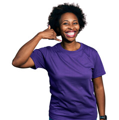 African american woman with afro hair wearing casual purple t shirt smiling doing phone gesture...