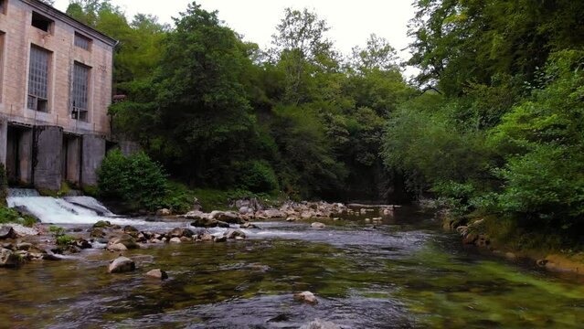 Abhesi waterfall among green trees, a mountain river with clear water. the stones are turned by the stream. Tourist place for rest and swimming. Aerial view. western Georgia Old water Mill