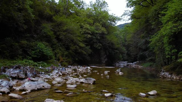 a mountain river with clear water among green trees. the stones are turned by the stream. Tourist place for rest and swimming. Aerial view. western Georgia, Abasha river Martvili