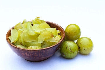 Phyllanthus emblica or Indian gooseberry sliced in a wooden bowl on white background side view 