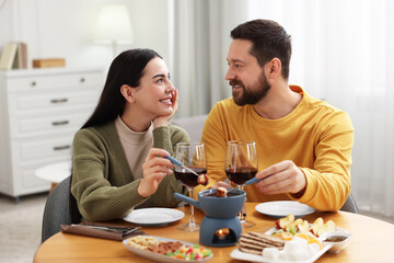Fototapeta na wymiar Affectionate couple enjoying chocolate fondue during romantic date at home