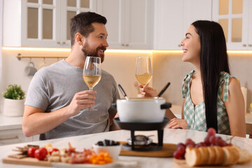 Romantic date with fondue. Couple with glasses of wine at home