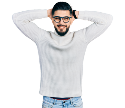 Young arab man with beard wearing elegant turtleneck sweater and glasses relaxing and stretching, arms and hands behind head and neck smiling happy