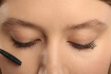 Woman applying mascara onto eyelashes, closeup view