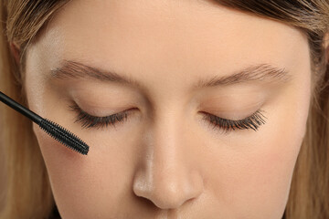 Woman applying mascara onto eyelashes, closeup view