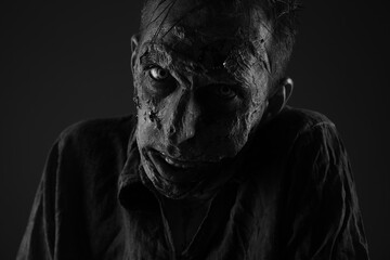 Scary zombie on dark background, black and white effect. Halloween monster