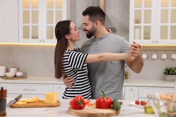 Happy lovely couple dancing together while cooking in kitchen