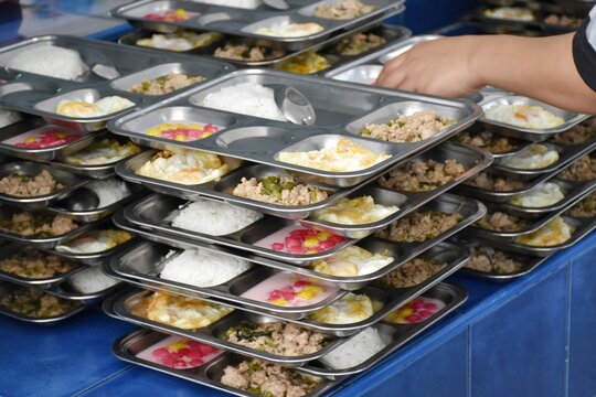 Various foods on stainless steel trays are arranged neatly on top of each other.